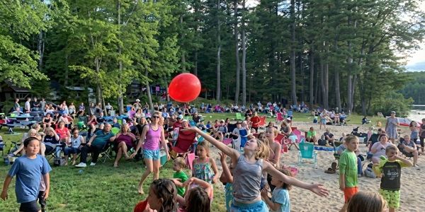 Group of friends sitting at an outdoor brewery table, enjoying craft beer and conversation with mountain views in the background