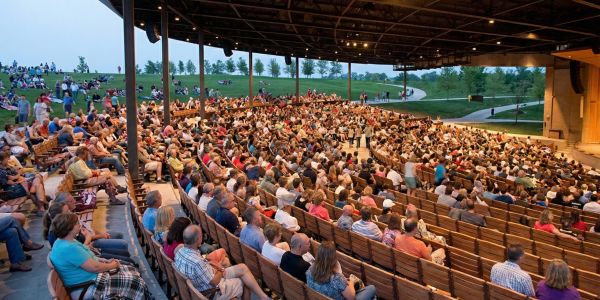 Group of friends sitting at an outdoor brewery table, enjoying craft beer and conversation with mountain views in the background