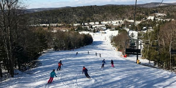 Group of friends standing in the snow with colorful snow tubes at a winter resort in the Catskills.