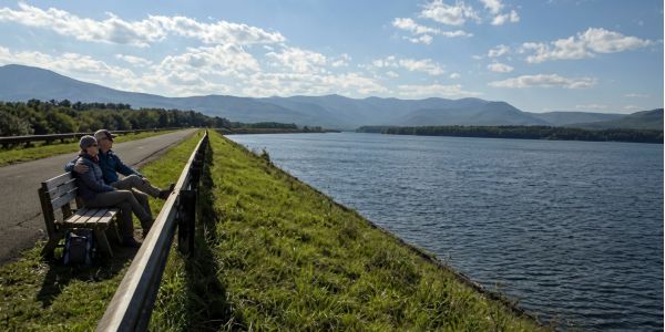 People riding a chairlift over colorful fall foliage with mountain views in the Catskills.