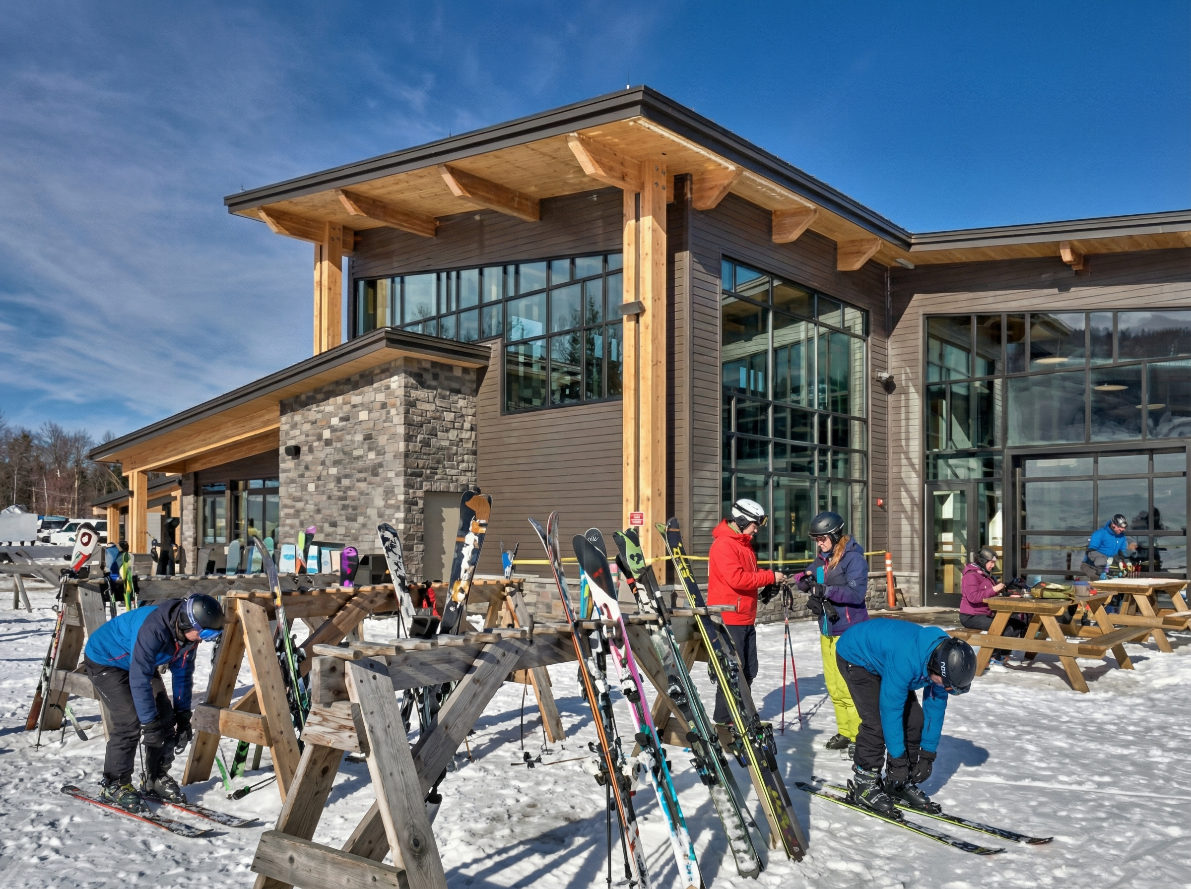 Couple in ski gear sitting on a wooden bench in the snow, sharing a warm drink during a winter day in the mountains